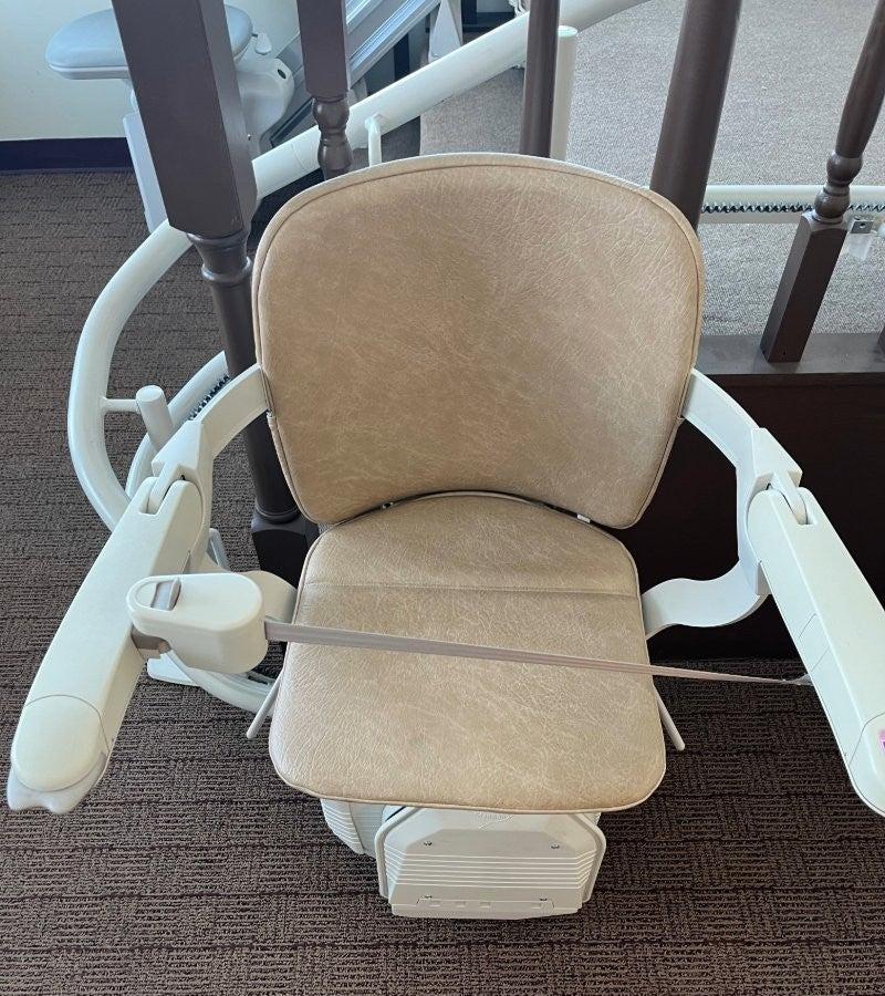 The Stannah Starla stairlift at the base of a set of stairs, with the seat belt buckled