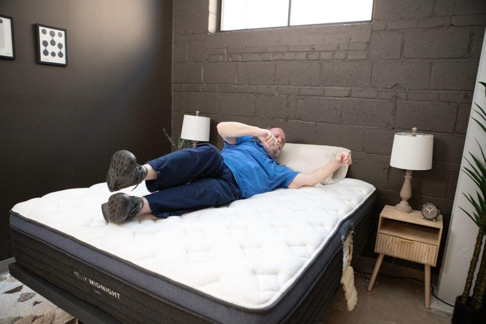 A man rolls over on top of a mattress