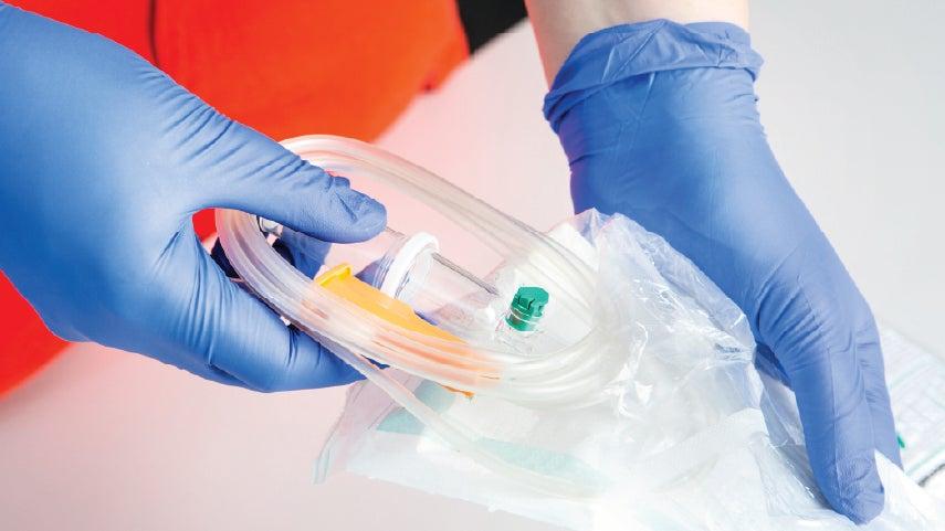 Gloved hands holding a packaged catheter