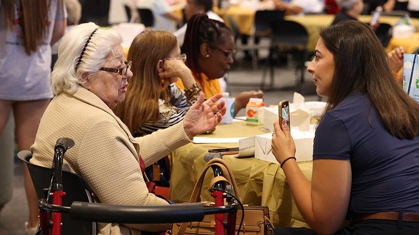 Two women sit at a table and talk to each other.