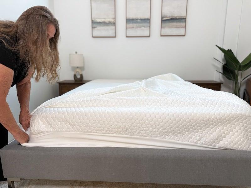 A woman puts the Bear GlacioTex mattress protector on a bed