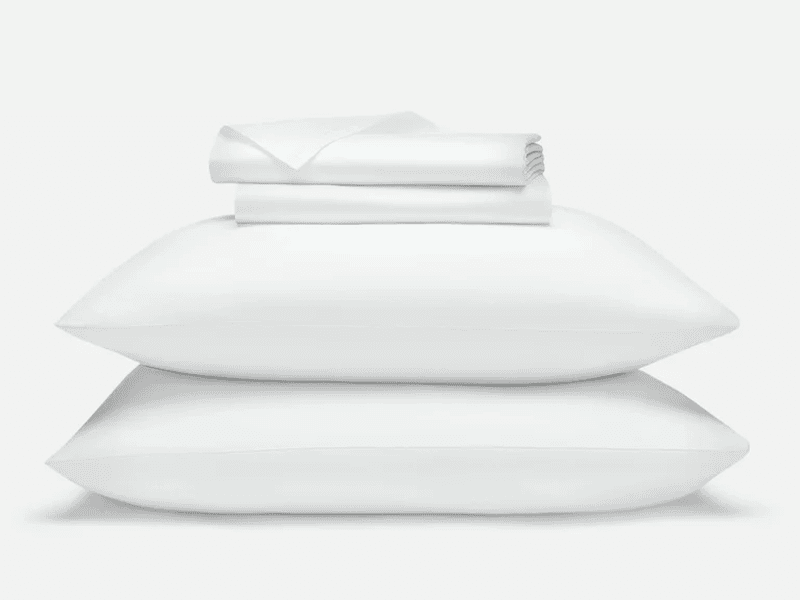 A stack of the Brooklinen Luxe Sateen Core Sheet Set and 2 pillows