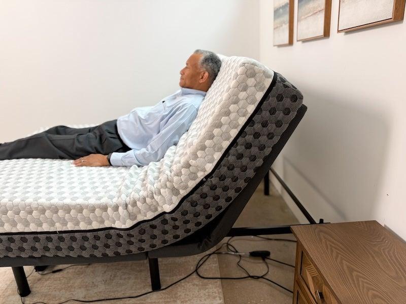 A tester lies on a mattress on the Nectar adjustable base with his head elevated