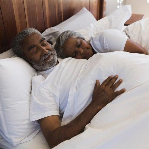 Man and woman sleeping in a bed with white sheets
