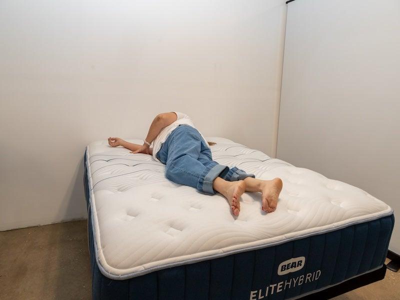 A woman rolling over onto her stomach on the Bear Elite Hybrid mattress