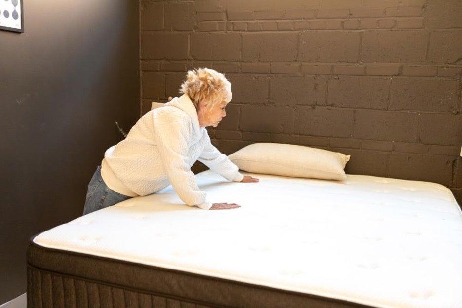 A woman presses down on the Titan Plus Luxe mattress