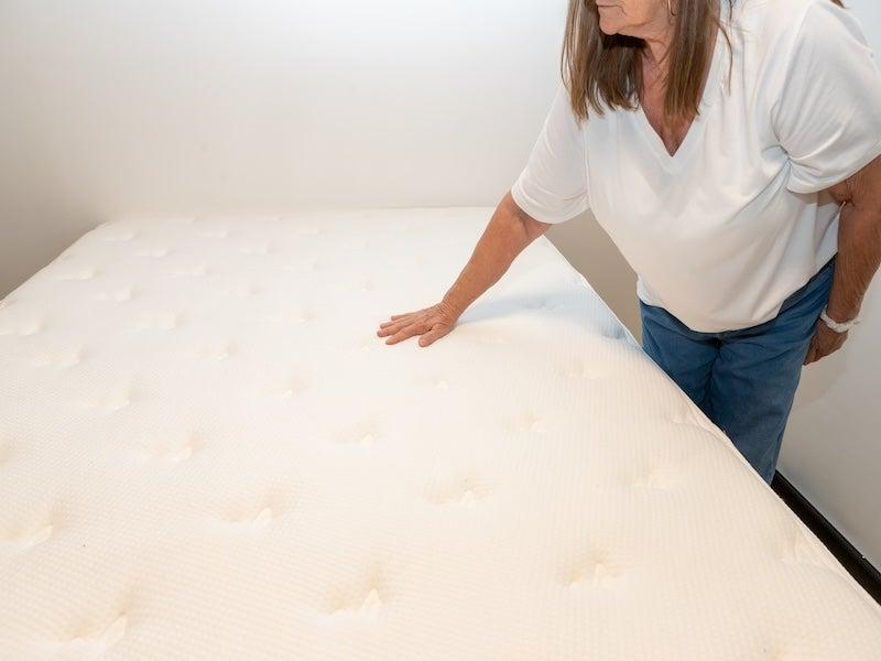 A woman touches the surface of the Brooklyn Bedding Signature Hybrid mattress.