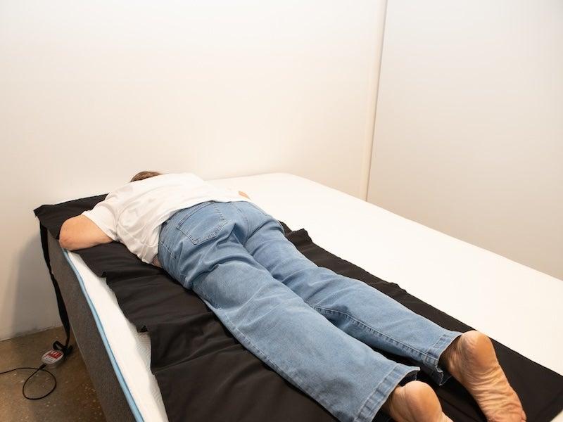 A woman lying on her stomach on a pressure map on top of a mattress