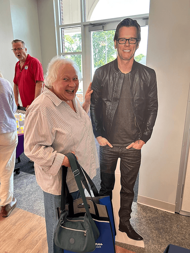 smiling older woman with cardboard Kevin Bacon
