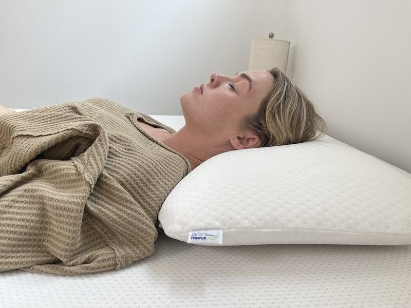 A woman lying on her back with her head on the Tempur-Symphony pillow