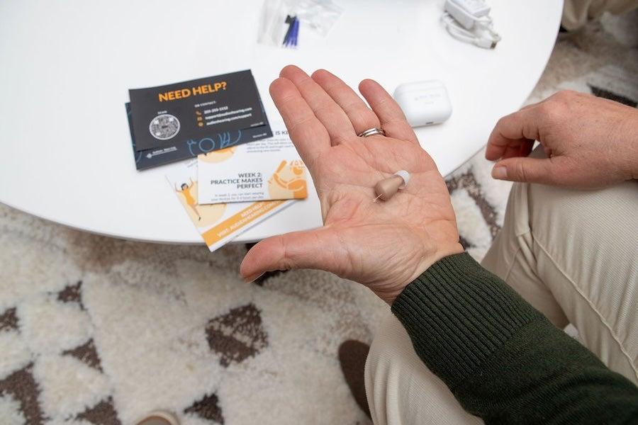 An Audien Atom Pro 2 hearing aid resting in a man’s hand