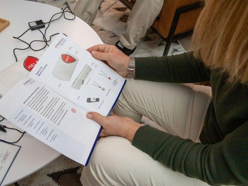 A woman reading the Medical Alert Home System user manual