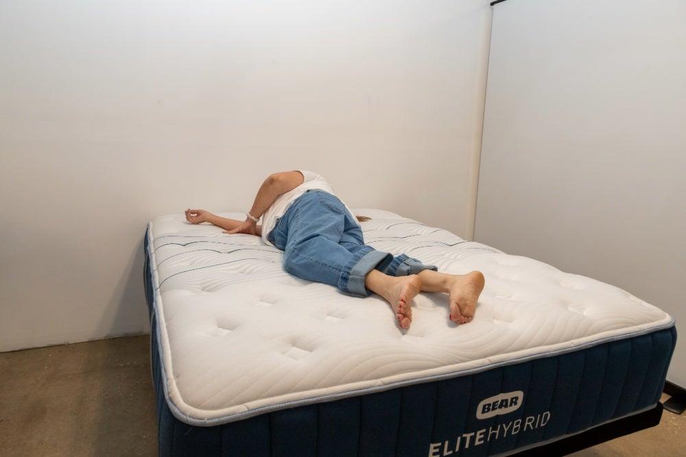 A woman lying on her side on the Bear Elite Hybrid mattress