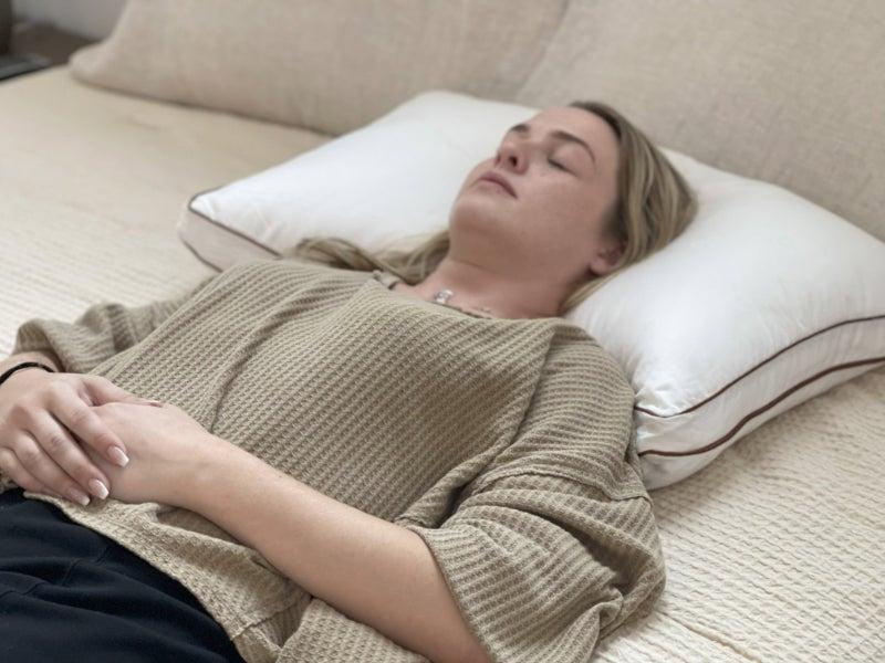 A woman sleeps on her back with the Saatva Latex pillow.