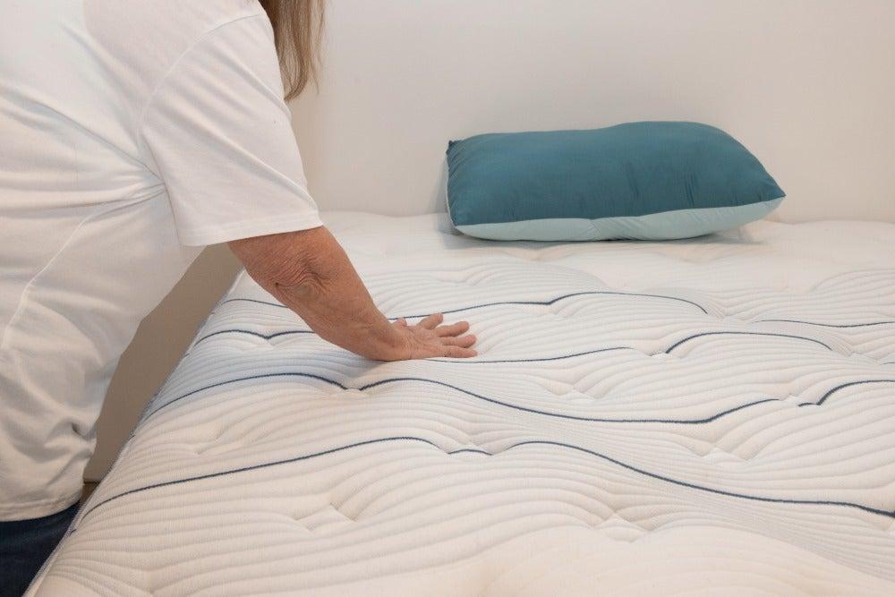 An older adult woman feeling the cooling cover of the Bear Elite Hybrid mattress