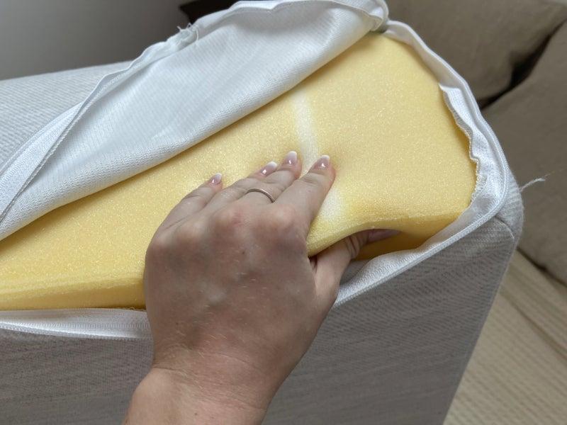 The Helix Wedge pillow with its cover unzipped and a hand squeezing its foam interior