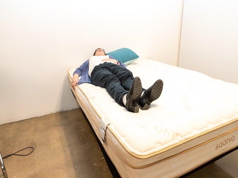 A woman lies on her back on the Saatva Class hybrid mattress