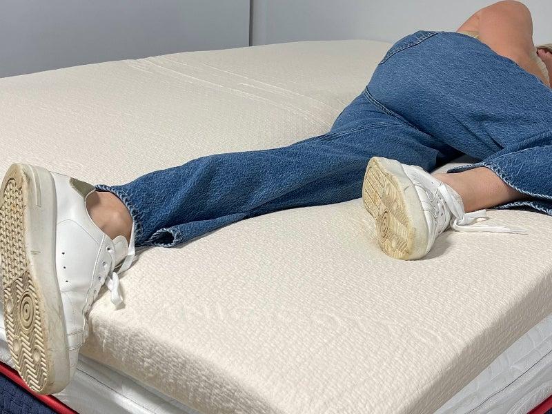 A woman lies on her side on the Avocado Eco Organic Latex mattress topper