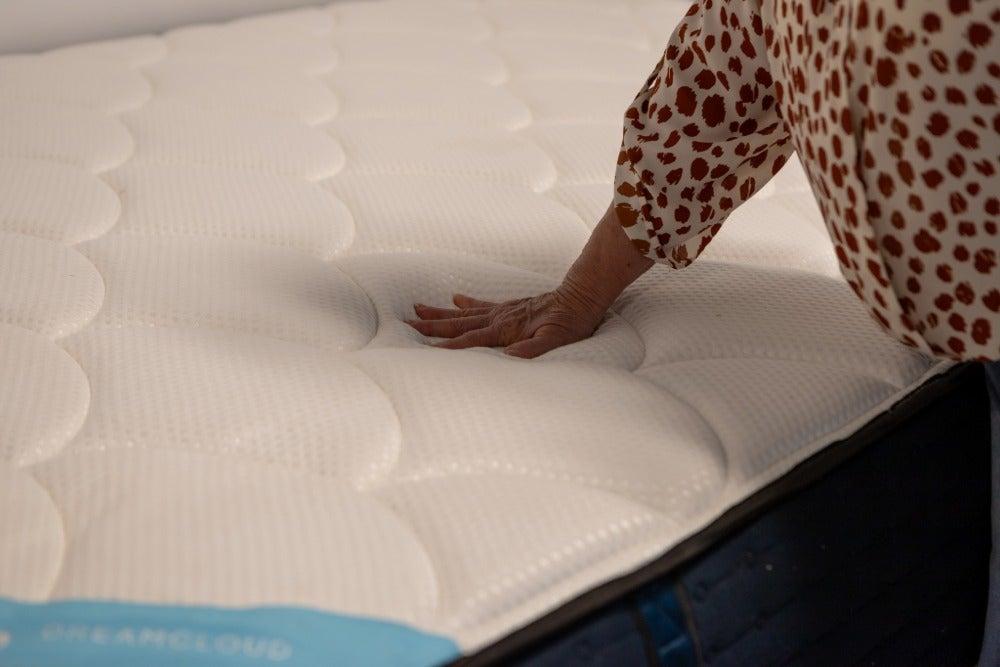 Woman’s hand presses down on the surface of the DreamCloud Premier Memory Foam
