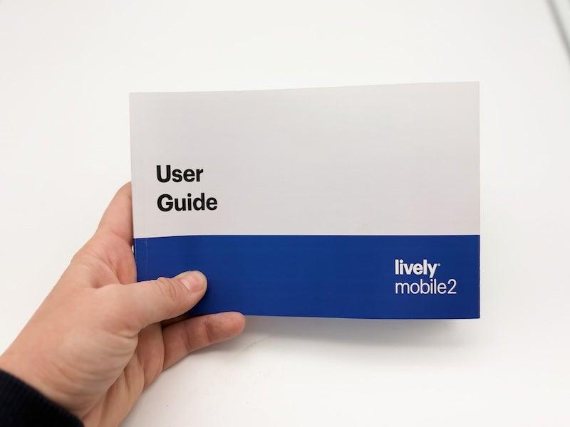 A hand holding the Lively Mobile2 medical alert system user guide