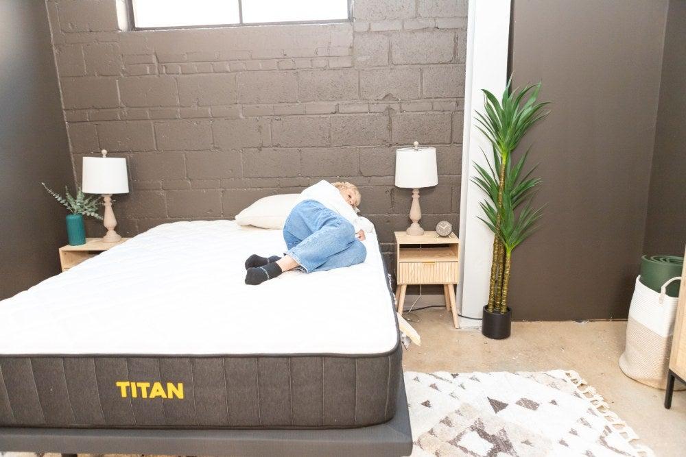 A woman lies on her side near the edge of the Titan Plus mattress