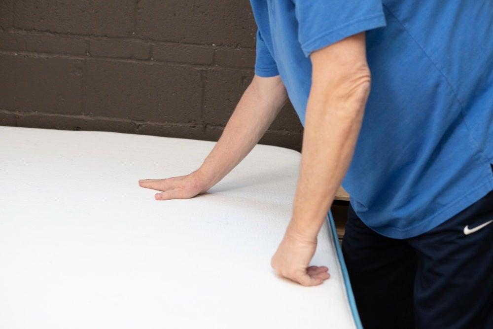 A man feeling the top of the Bear Original mattress