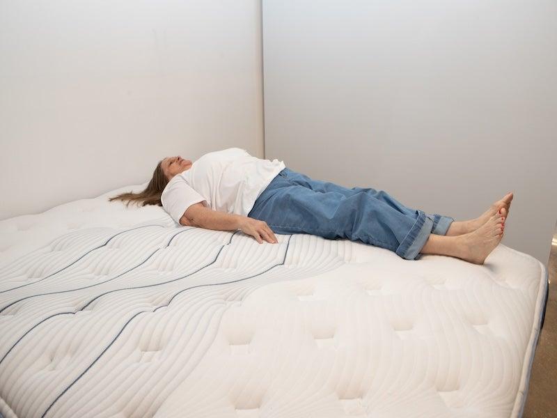 A woman lies on her back on the Bear Elite Hybrid mattress.
