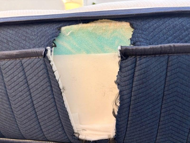 The Silk & Snow hybrid mattress with a hole cut into the outside fabric, showing a foam interior