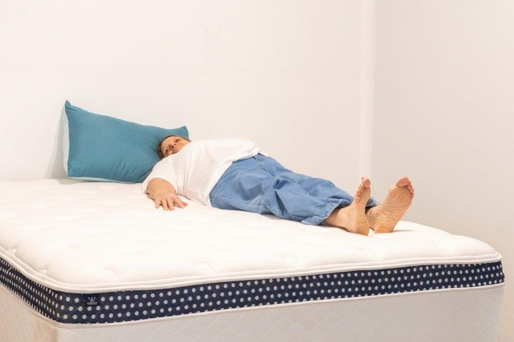 A woman lies on her back on a mattress