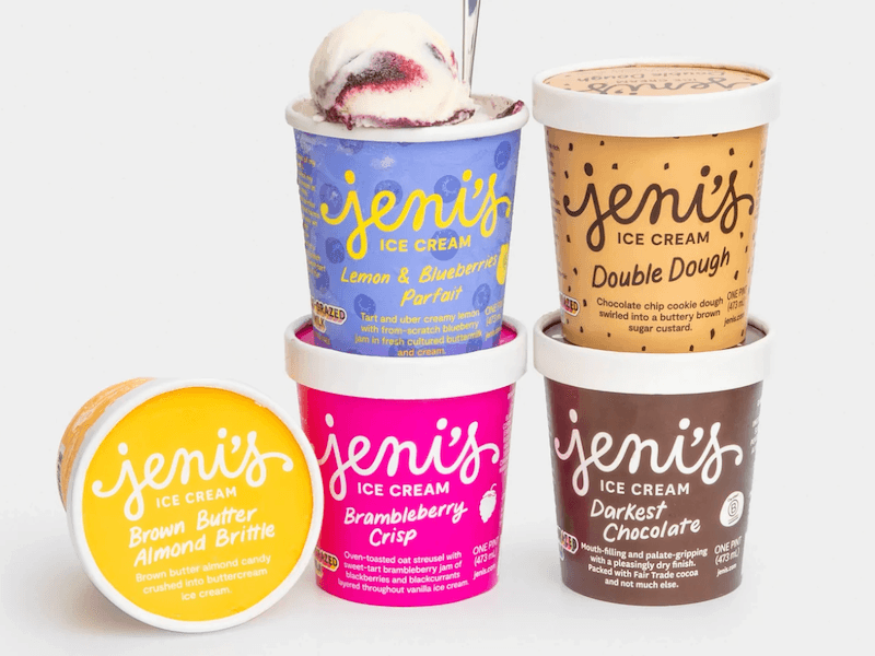 Five Jeni's ice cream pints stacked; Lemon & Blueberry Parfait with a spoon, Double Dough, Brown Butter Almond Brittle, Brambleberry Crisp, and Darkest Chocolate