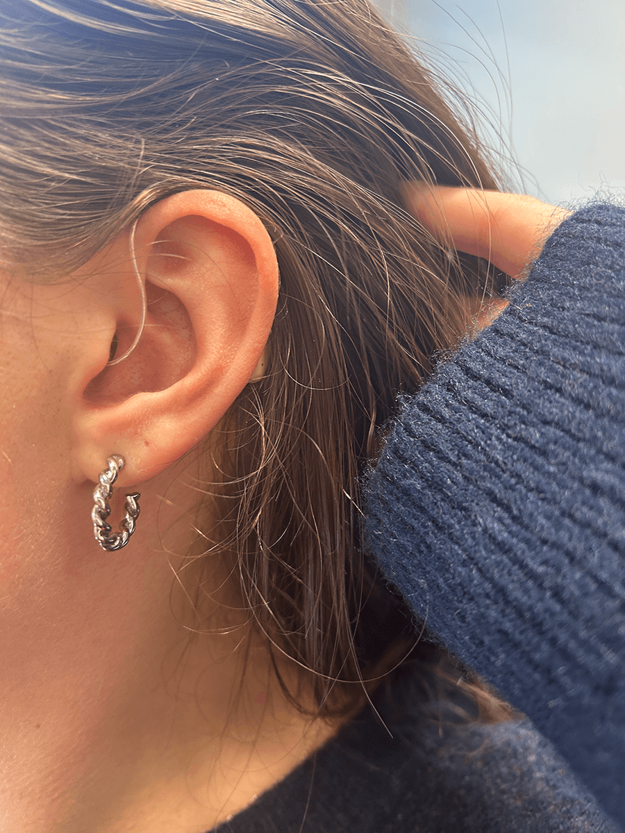 A woman pulling her hair away from her ear to show the Audien Ion Pro