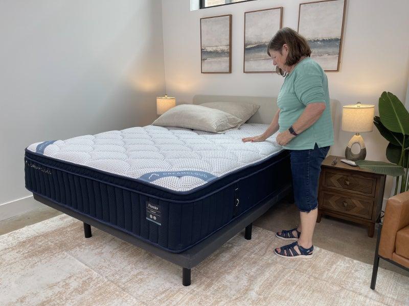 A woman touching the cover of the DreamCloud Classic Hybrid