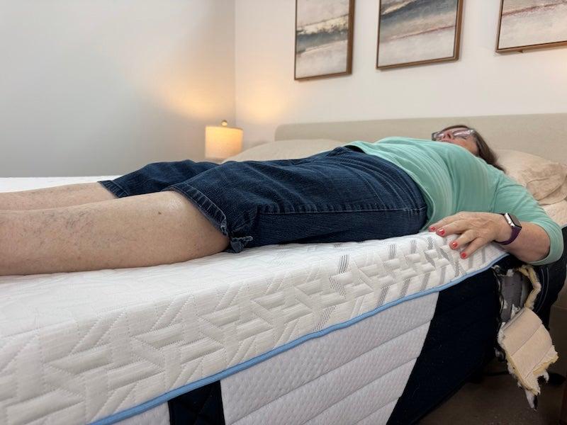A woman lies on her back near the edge of the Nectar Classic Hybrid mattress.