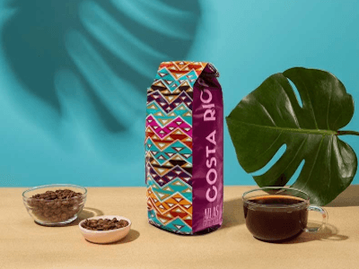 Bag of Costa Rican coffee in a display with dishes of coffee beans and a cup of coffee.