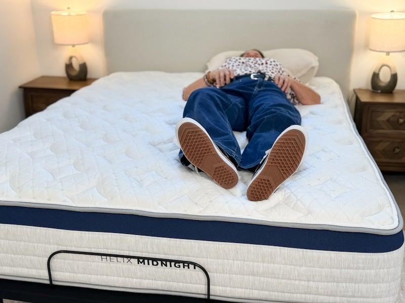 A woman lying on her back on the Helix Midnight hybrid mattress