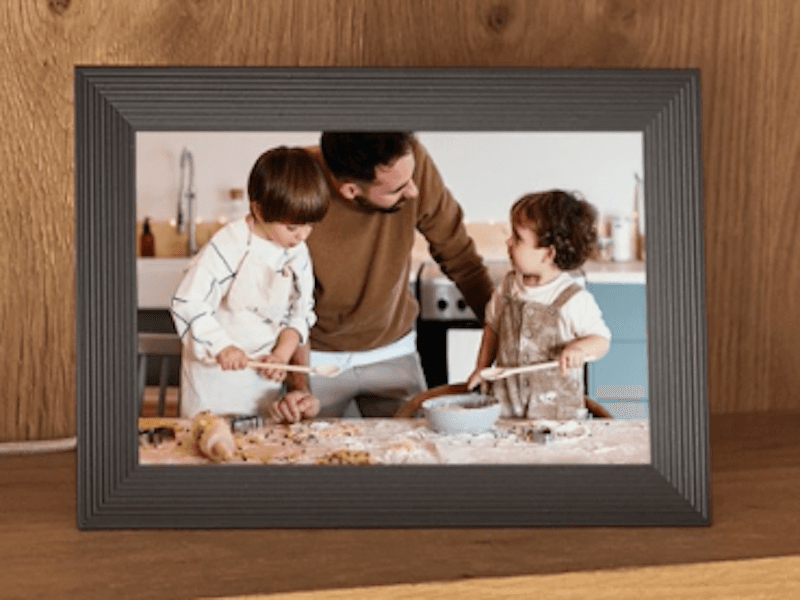 Wooden picture frame displaying a smiling adult and two children baking in a kitchen.