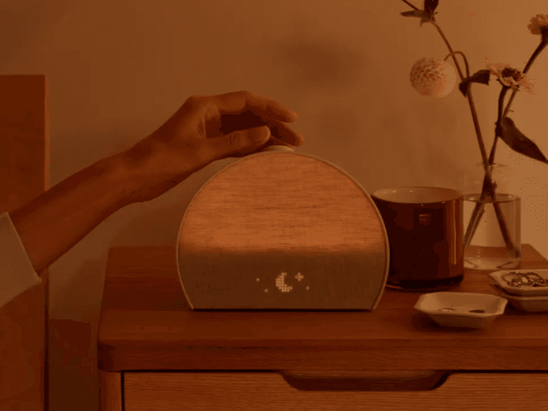 Hand reaching for button on top of Hatch Restore 3 Alarm Clock.