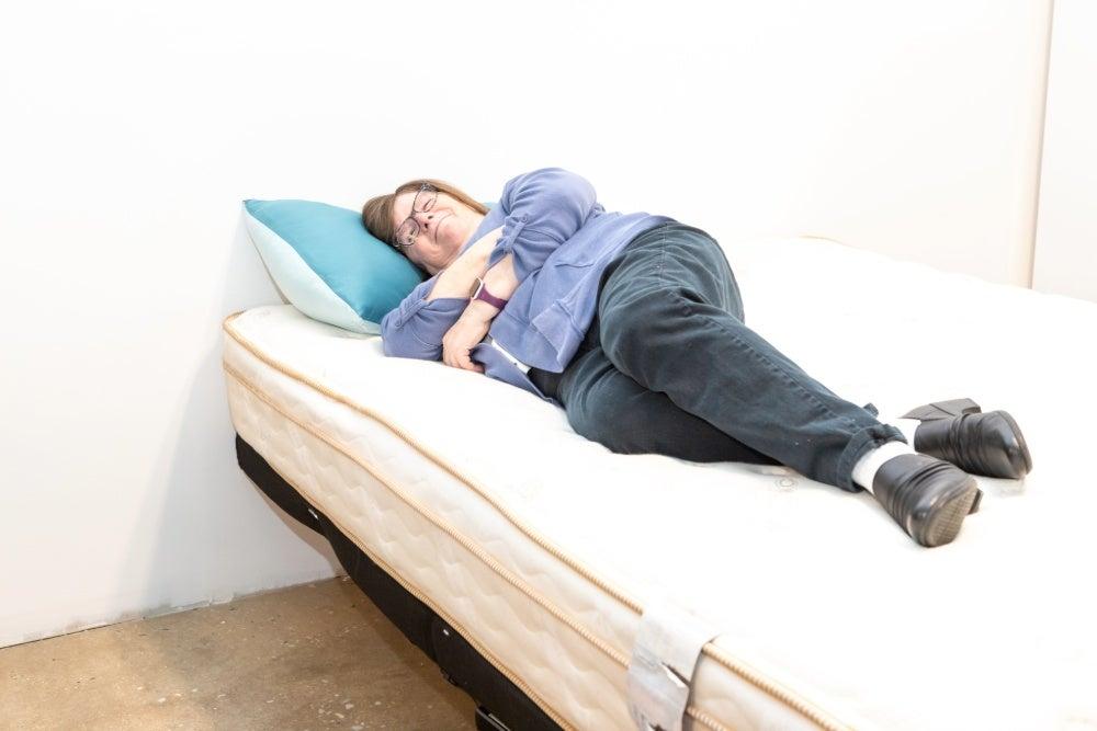 Woman lies on her side on a mattress while smiling