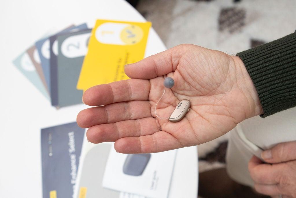 a hearing aid shown in the palm of a man's hand