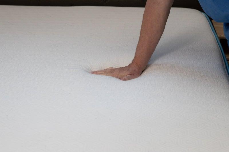 A hand pressing down on the cover of the Bear Original mattress