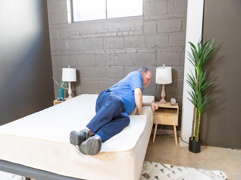 A man rolls onto his side on the Birch Natural latex hybrid mattress.