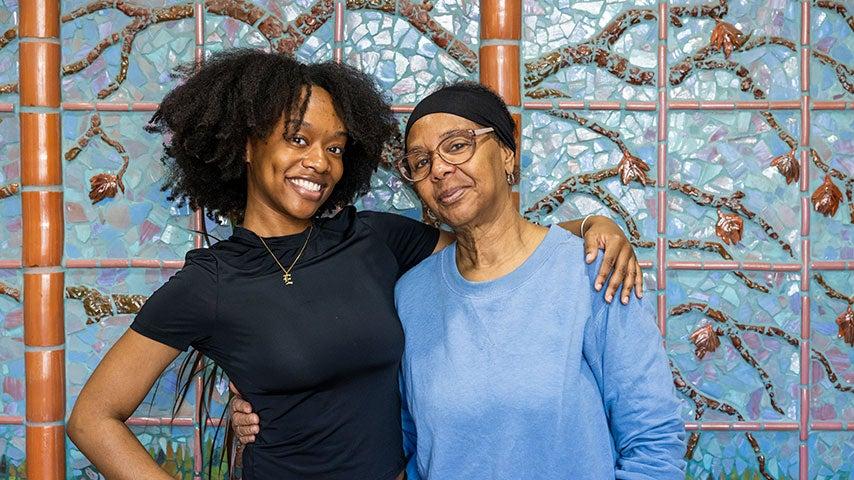 Smiling senior center staff member and participant with arms around each other