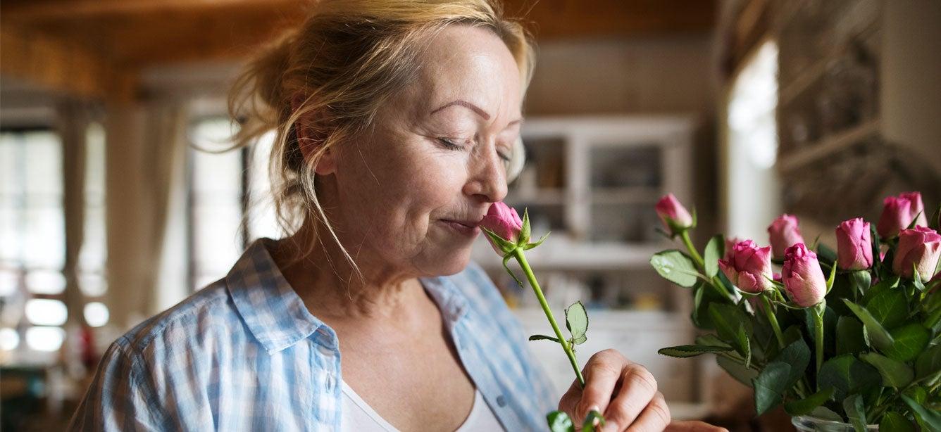 A caregiver of an older adult is taking time to smell the roses in her kitchen. A brief respite from burnout and exhaustion.