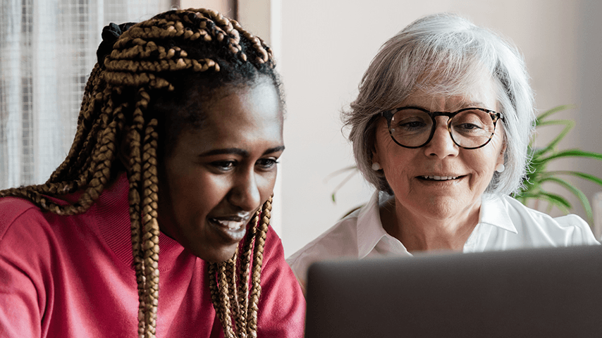younger black woman and older white woman looking at laptop screen