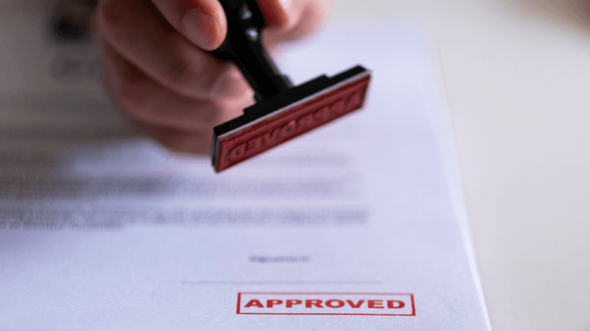 A hand holding an approval stamp