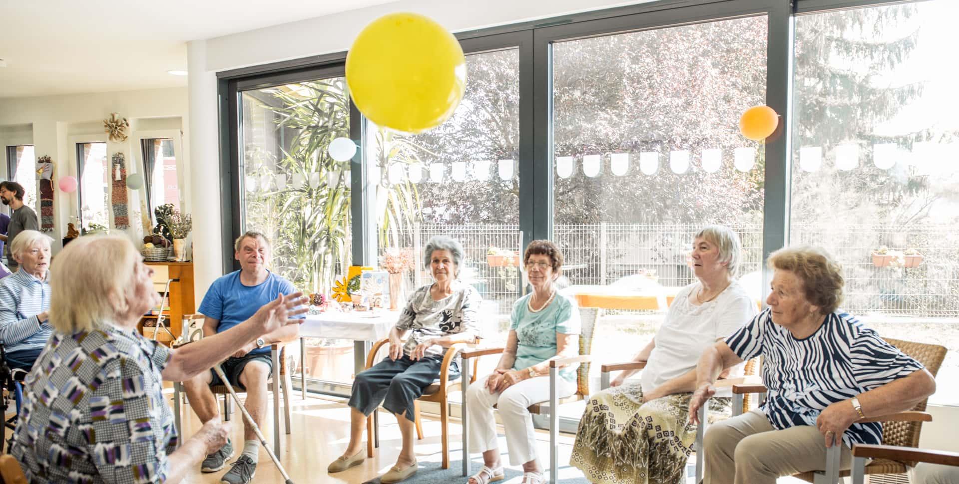 Group of seniors gathered together in a room at a senior center for a party.