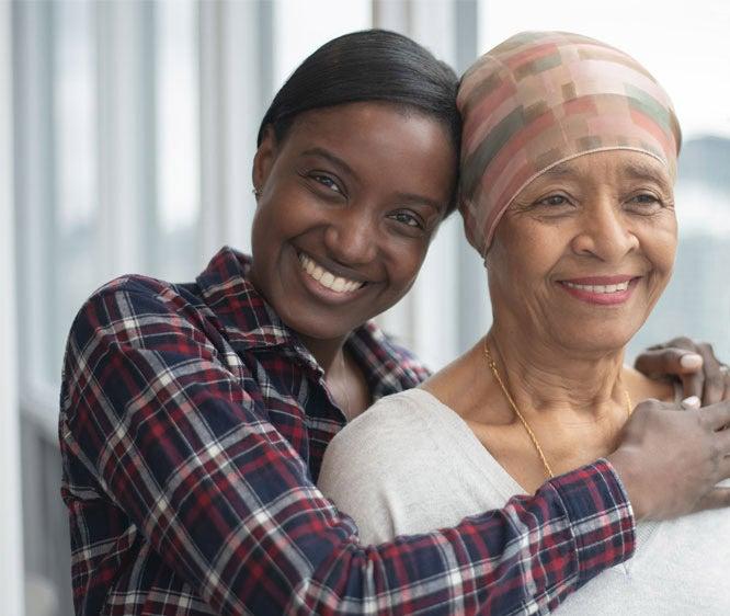 A Black senior woman is being hugged by her caregiver, daughter.