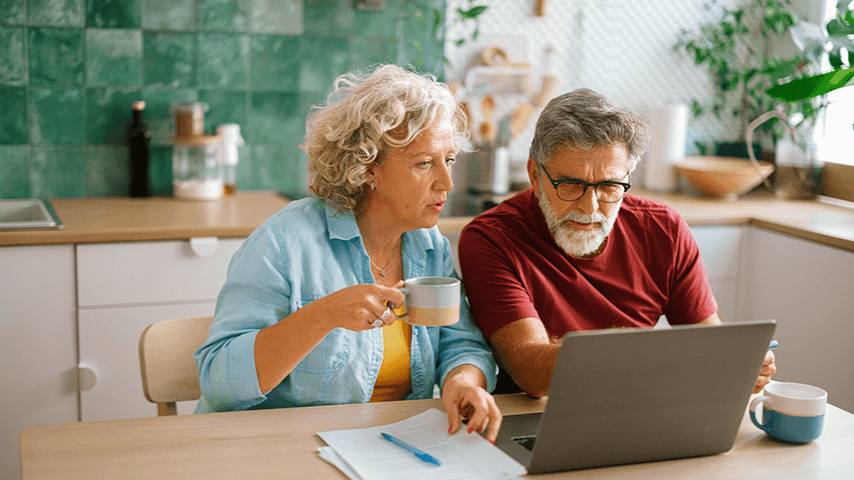 older couple looking at bills and laptop screen
