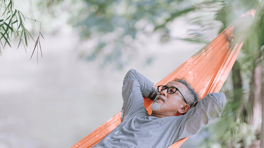 older Asian man asleep in an outdoor hammock