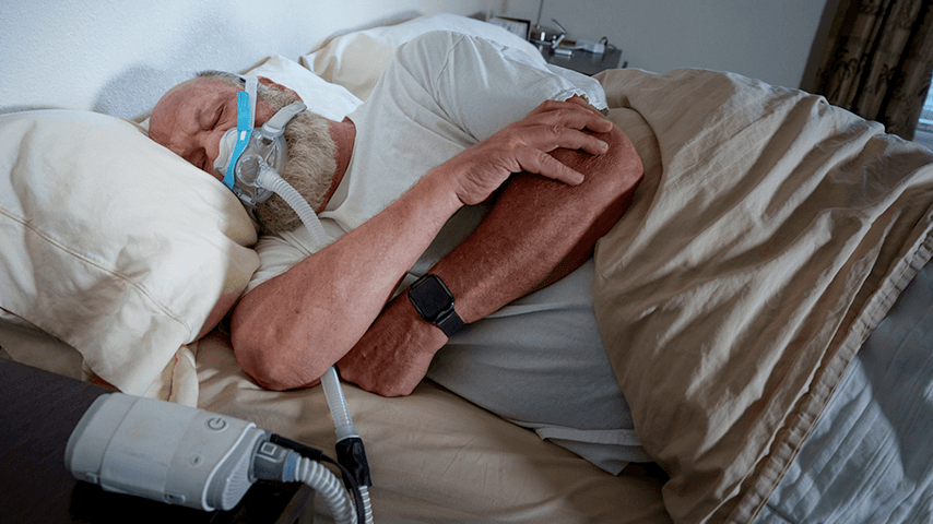 older white man asleep on side with CPAP mask on